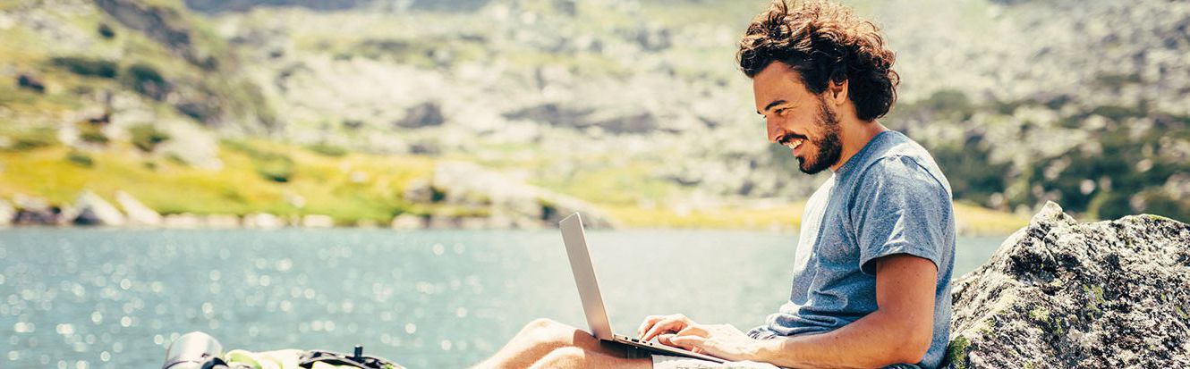 man on laptop by river